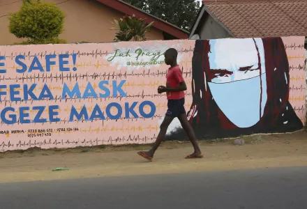 A young boy walks past a wall with graffiti urging people to wear face masks in Harare, Thursday, May, 28, 2020.