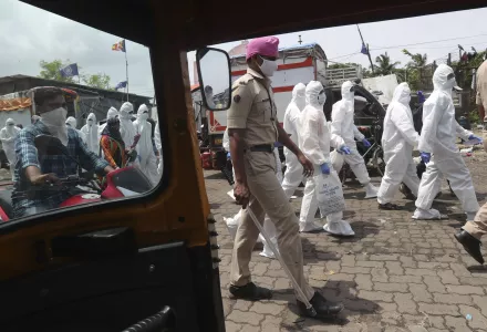 Health workers escorted by policemen arrive to screen people for COVID-19 symptoms at a slum in Mumbai, India, Friday, July 10, 2020.