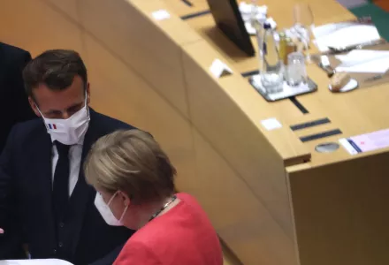 French President Emmanuel Macron, second right, looks over papers with German Chancellor Angela Merkel, right, during a round table meeting at an EU summit in Brussels, Monday, July 20, 2020. 