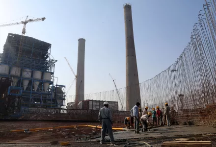 Workers lay cement to build a concrete structure at a coal-fired power plant