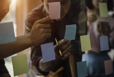 Office workers using sticky notes on a wall