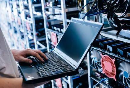 A technician holding a laptop working in a server room