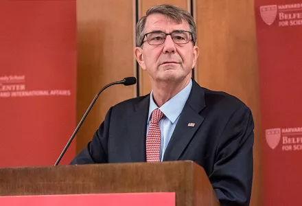 Ash Carter standing at a podium in front of crimson Belfer Center backdrops.