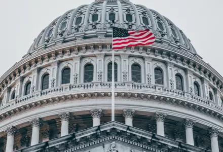 A detail of the U.S. Capitol dome with the American flag flying.