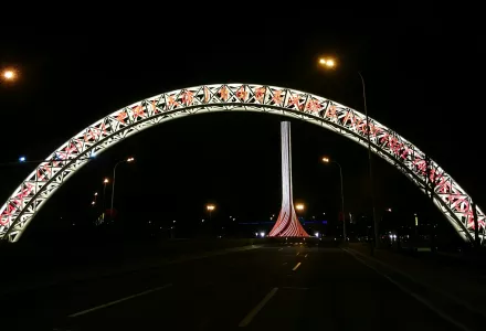 Gate of Tianjin Free-Trade Zone. A brightly lit arch over a nighttime roadway. A brightly lit pillar appears in the background.
