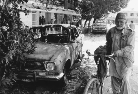 An old man walks past a gutted car in downtown Kabul, Thursday, June 25, 1992. 