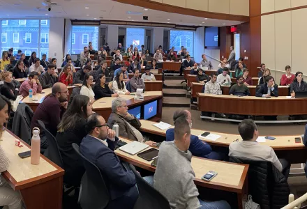 A wide panporama of a full auditorium with former Colombian President Ivan Duque at the far right edge of the image.