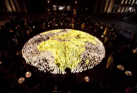 People stand around about 5000 candles arranged to form a globe in front of the Brandenburg Gate, Berlin, Germany, March 31, 2012.
