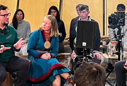 Speakers and audience sit in a circle inside a lavvu-style tent, in Norway.
