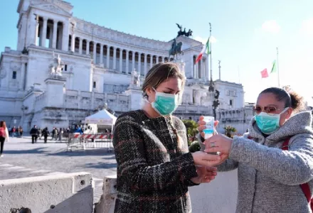Women wearing face mask disinfect their hands in central Piazza Venezia, Rome