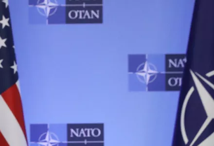 U.S and NATO flags in front of a NATO conference backdrop.