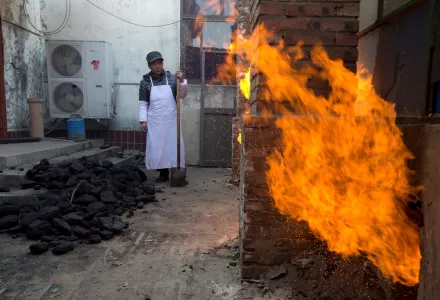 A worker waits to shovel coal to feed kitchen stoves at the Liuminying village in Beijing, China