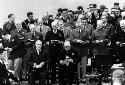 U.S. President Franklin D. Roosevelt, seated left, and British Prime Minister Winston Churchill, right, join in the singing during church services aboard the Battleship HMS Prince of Wales