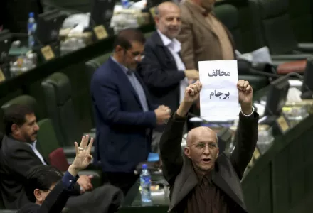 Iranian conservative lawmaker Bijan Nobaveh Vatan holds up a paper with writing in Persian reading, "Opponent of the JCPOA"