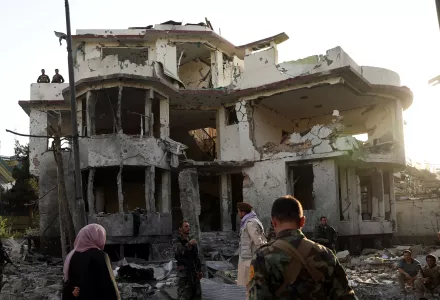 Afghan security personnel inspect a damaged building