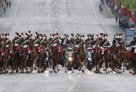 Emmanuel Macron waves from a military vehicle while riding on the Champs Elysees