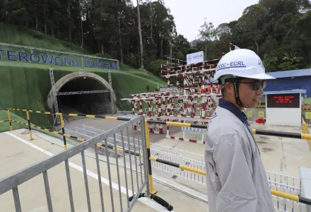 A worker stands near a tunnel