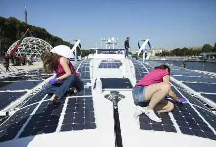 Crew members of the Energy Observer, a former race boat turned into a autonomous navigation with hydrogen, clean the solar panels of the boat in Paris