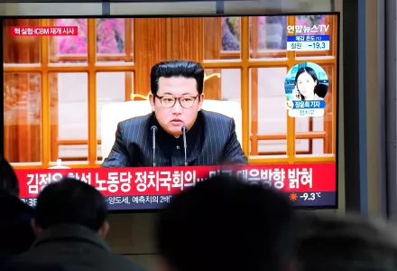People watch a TV showing a file image of North Korean leader Kim Jong Un shown during a news program