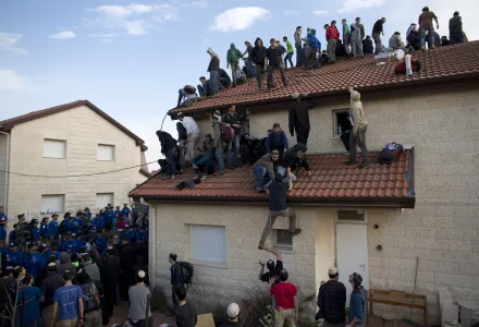 Settlers climb on a roof as Israeli police are evicting them the West Bank settlement of Ofra