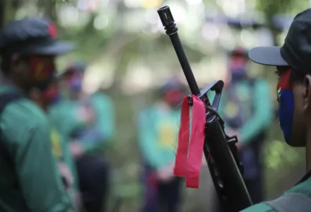 red ribbon is tied to a firearm of a New People's Army guerrilla in the Philippines
