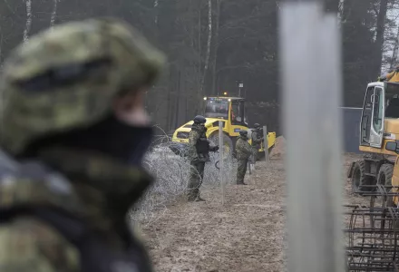 Military watching the start of work on the first part of some 180 kilometers of a 5.5 meter-high metal wall