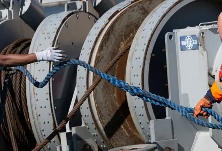Ship engineer Wim Giabeler, right, and deckhand Gerard Bakulikira, left, wear Romware COVID Radius digital bracelets as they work on deck of a tugboat in the Port of Antwerp, Belgium. The Romware ONE bracelet will allow employees to resume work safely as the bracelet monitors physical distance and traces contacts.