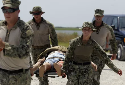 U.S. Navy Master-at-Arms Third Class Danielle Hinchliff, right, of Coastal Riverine Squadron 2, helps carry a mock wounded person