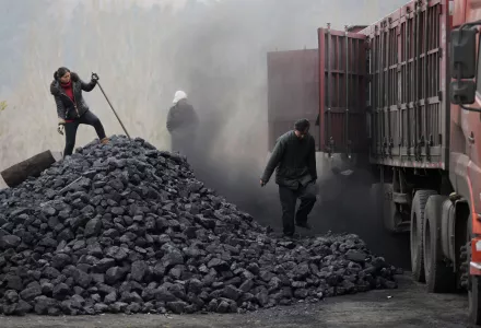 Workers load coal from a truck at a process station for sale in Tangxian in China's Hebei province.