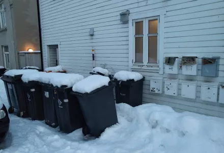 Waste bins on a snowy sidewalk in Tromso, Norway.
