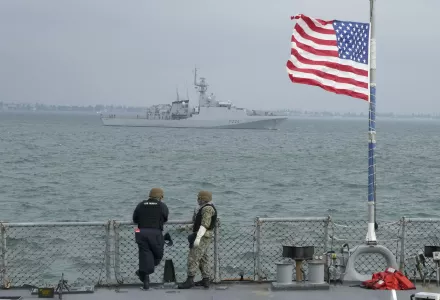 Members of the U.S. Navy of the Arleigh Burke-class guided-missile destroyer USS Ross look on Britain's Royal Navy patrol ship 