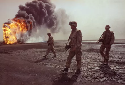 In this March 7, 1991 file photo, a U.S. Marine patrol walks across the charred oil landscape near a burning well during perimeter security patrol near Kuwait City.