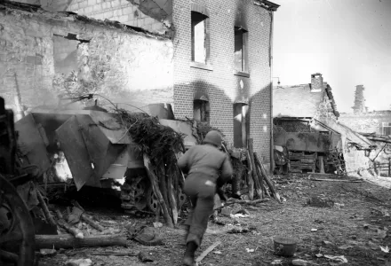 An American soldier runs past a burning German half-track in the recaptured town of La Gleize, Belgium, in 1944 during the Battle of the Bulge in World War II.