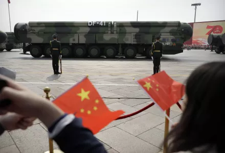 Spectators wave Chinese flags as military vehicles carrying DF-41 nuclear ballistic missiles roll during a parade to commemorate the 70th anniversary of the founding of Communist China in Beijing on Oct. 1, 2019.