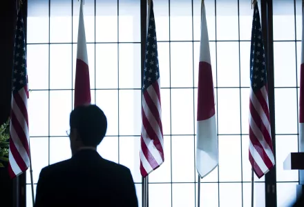 A man walks in front of Japan and the US flags during the 60th anniversary commemorative reception of the signing of the Japan-US security treaty at the Iikura Guesthouse in Tokyo, Sunday, Jan. 19, 2020.