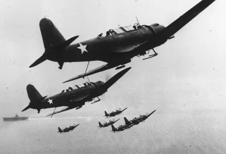 Six U.S. Navy scout planes in flight above their carrier