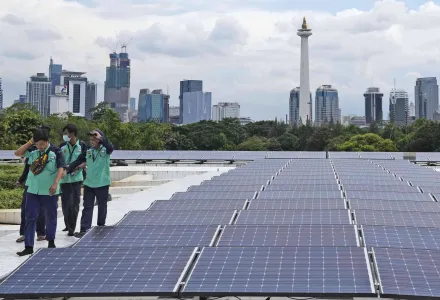 Workers walk near solar panels that provide partial electrical power to Istiqlal Mosque as the city skyline is seen in the background, in Jakarta, Indonesia, Wednesday, March 29, 2023. (AP Photo/Tatan Syuflana)