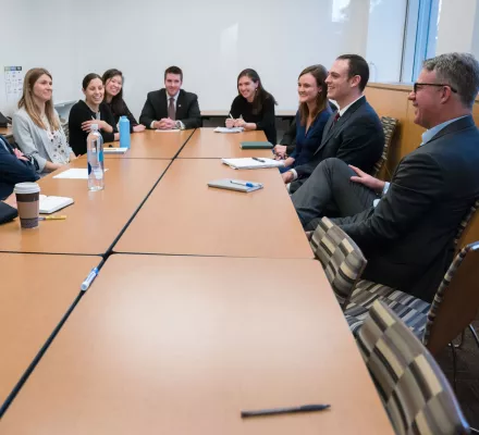 Ash and students sitting around a table laughing.