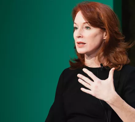 Meghan O'Sullivan speaking in front of a green background.