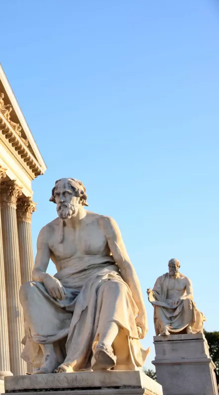 Statue of Thucydides and temple with low angle sun.