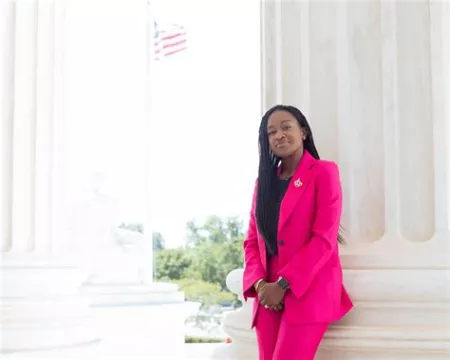 Camille Steward Gloster in front of a column in a pink suit. 