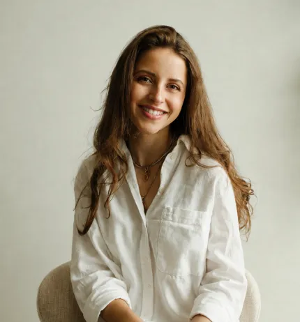 A woman dressed in white sits facing the camera.